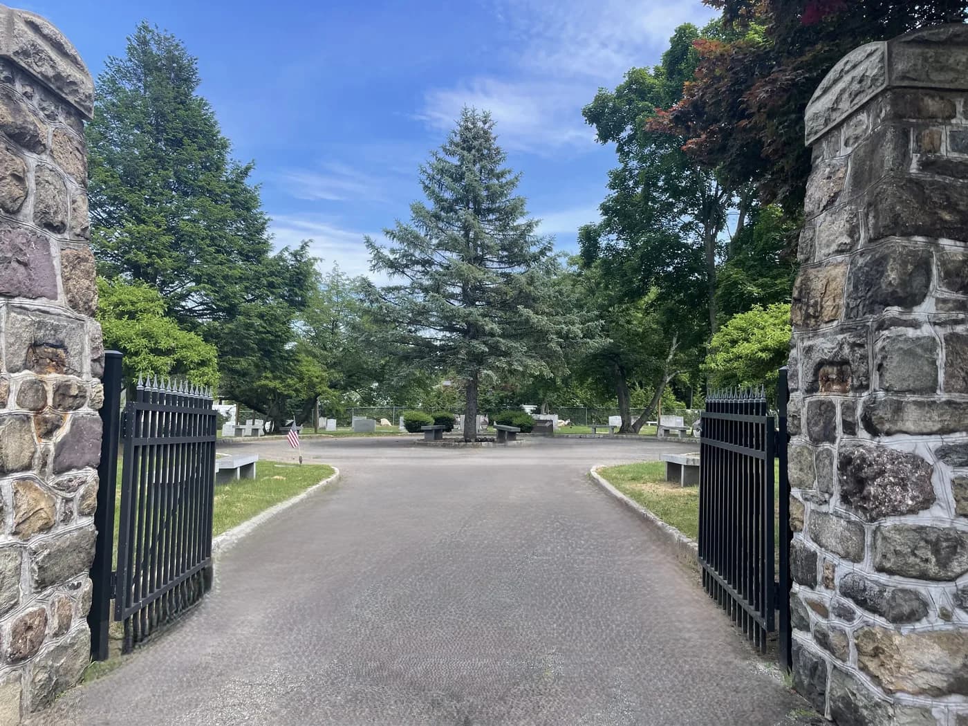 Stone gateposts and open iron gates at the entrance to Beth Israel Memorial Park.