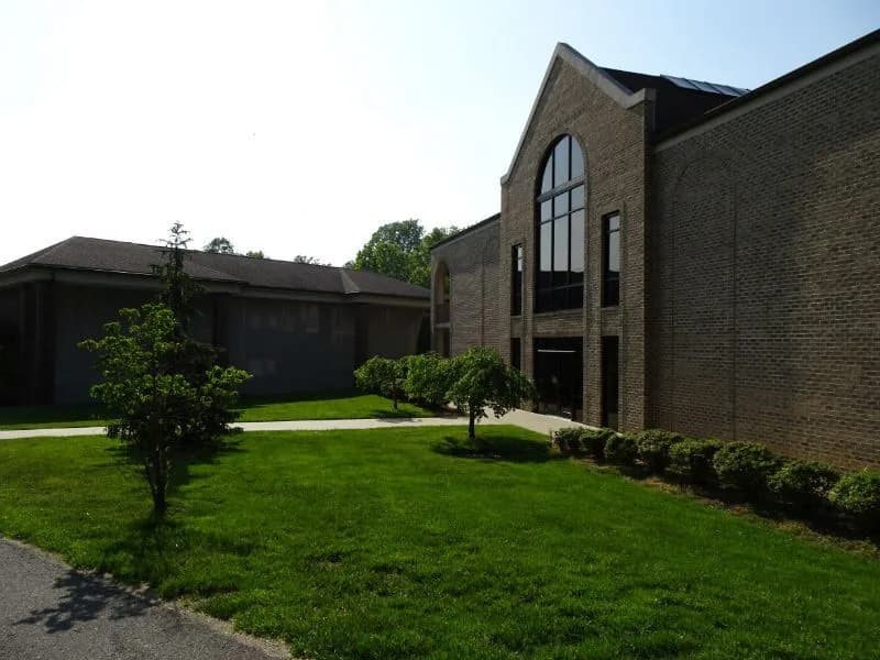 The brick mausoleum building at Holmdel Cemetery, seen across the lawn.