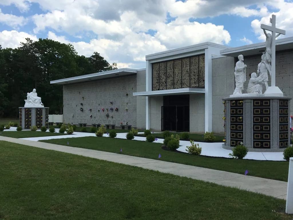 The mausoleum at Holy Cross Cemetery, with white statuary of the Crucifixion beside it.