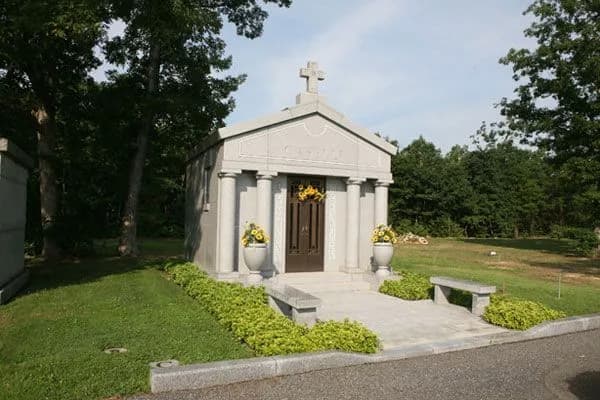 A small granite mausoleum with a cross on its roof at Our Lady of Victories Cemetery.