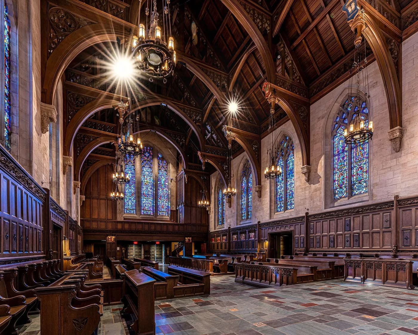 The vaulted interior of the Princeton Abbey chapel, with stained glass and carved wooden pews.