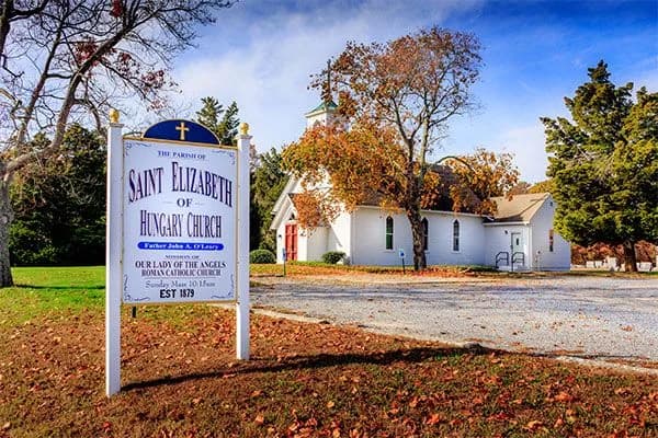 The white church of Saint Elizabeth of Hungary beside its parish sign.