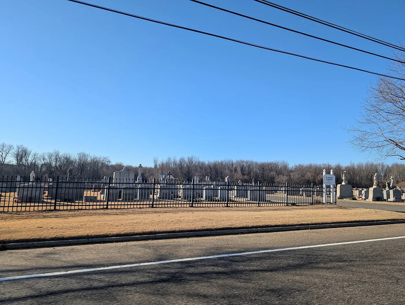 St. Joseph Cemetery seen from the road, behind an iron fence.