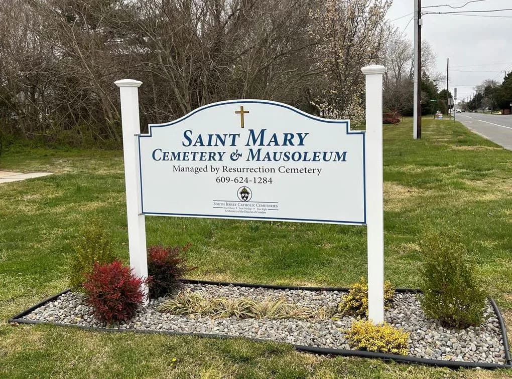The Saint Mary Cemetery & Mausoleum sign in a planted bed by the road.